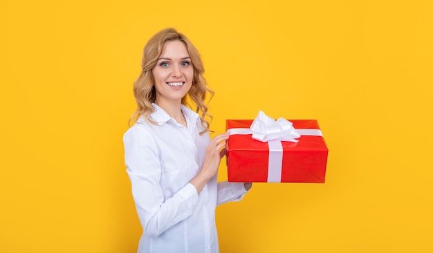 Happy woman hold big present box on yellow background