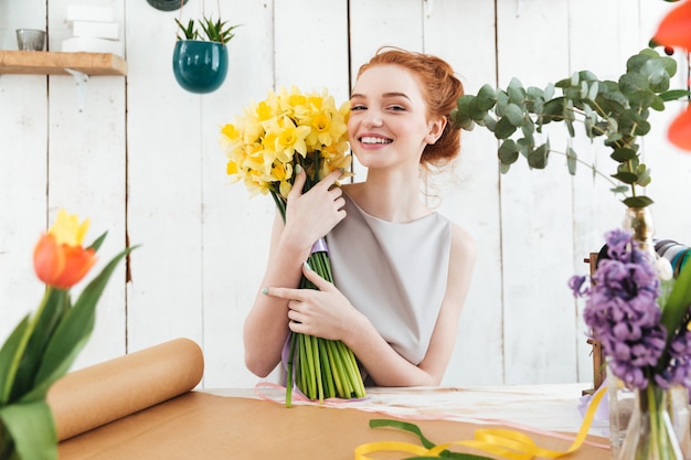 Happy woman holding beautiful bouquet of yellow flowers while working