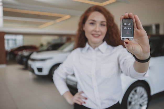 彼女の新しい自動車に車のキーを保持している幸せな女