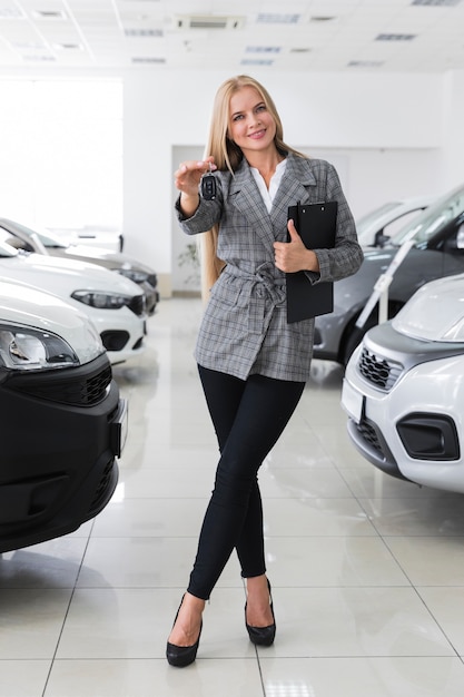 車のキーのロングショットを保持している幸せな女