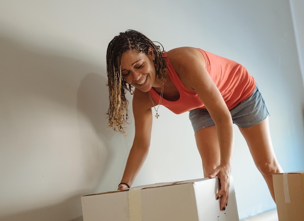 Photo happy woman holding cardboard box against wall