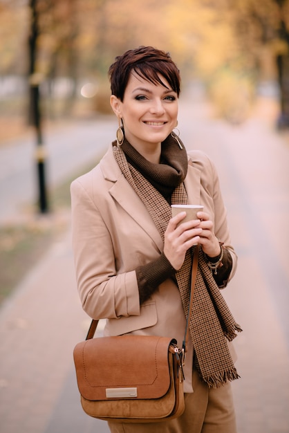 Фото Счастливая женщина держит чашку кофе в руке и улыбается