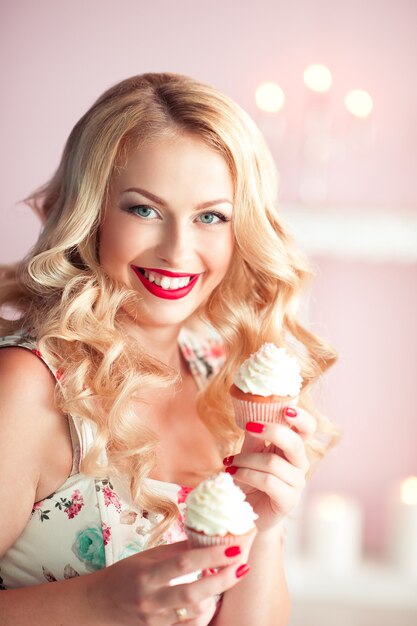 Happy woman holding cupcakes over christmas lights