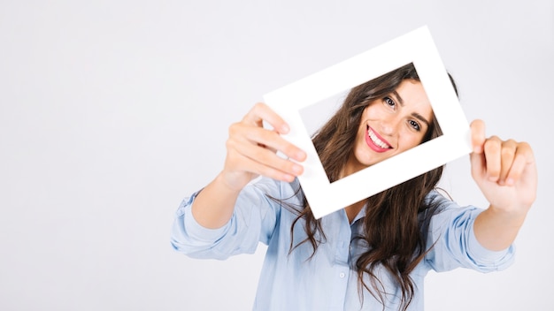 Photo happy woman holding frame in front of face