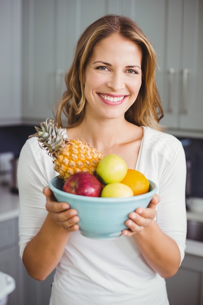 Happy woman holding a fruit bowl 