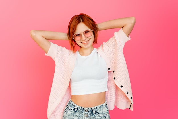 Happy woman holding hands over her head smiling on pink background