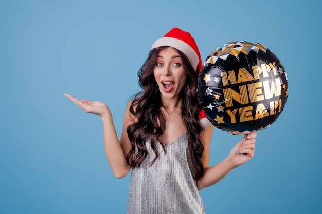 Happy woman holding happy new year balloon and wearing santa hat