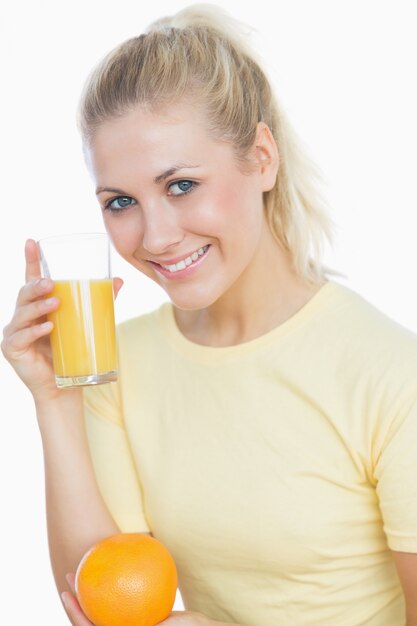 Happy woman holding juice and orange