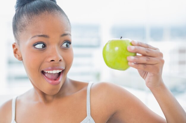 Happy woman holding and looking at green apple