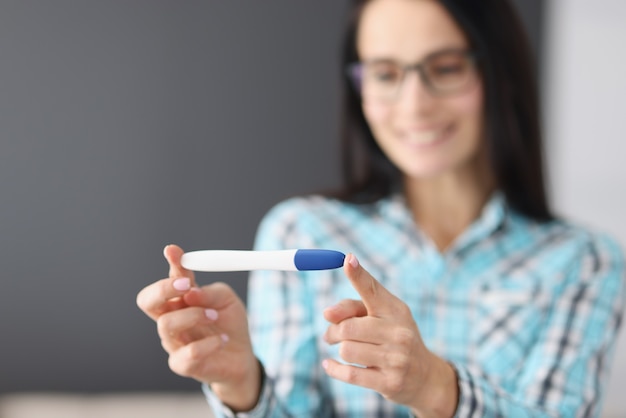 Happy woman holding pregnancy test in her hands and smiling closeup