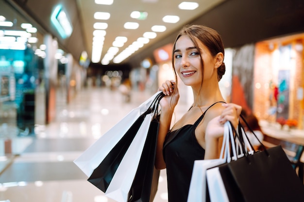 Happy woman holding shopping bags and smiling at the mall