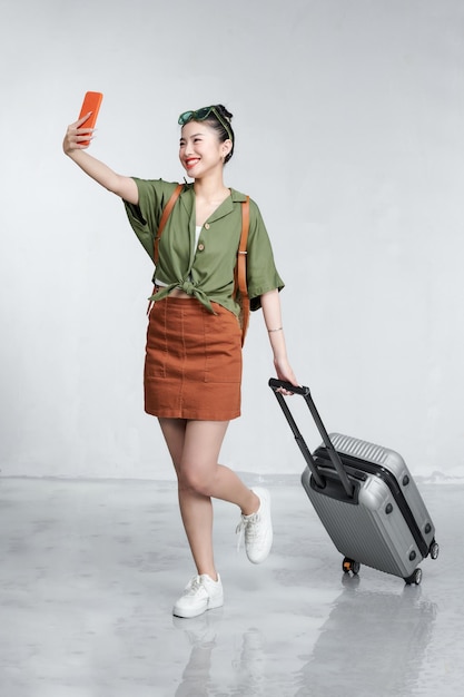 흰색 배경 위에 스마트폰과 여행 티켓을 들고 있는 행복한 여성