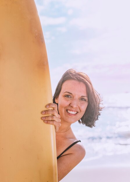 Happy woman holding a surfboard