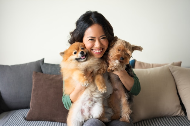 快乐的女人照片持有约克夏和猎犬的狗在沙发上