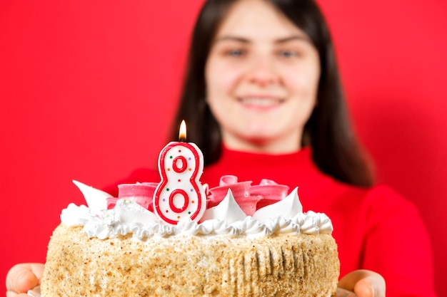 A happy woman holds a cake with a candle