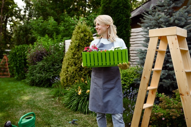 Happy woman holds flower bed in the garden