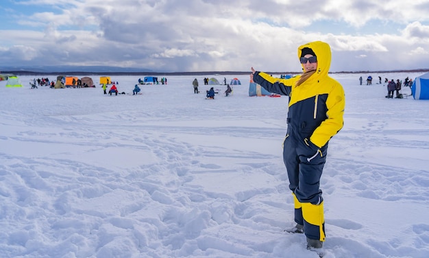 Happy woman on the ice of the seaActive vacationWinter fishing