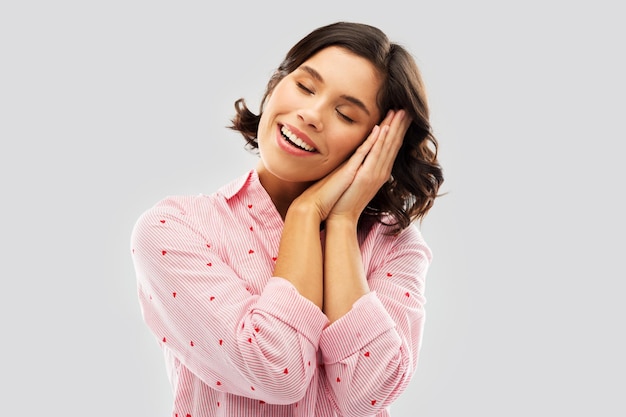 Фото Счастливая женщина в пижаме делает сонный жест.