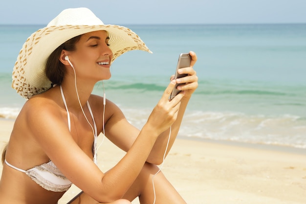 행복 한 여자는 해변에서 음악을 듣고있다