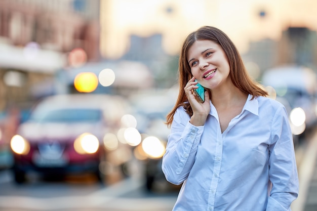 Happy woman is talking by phone near motorway