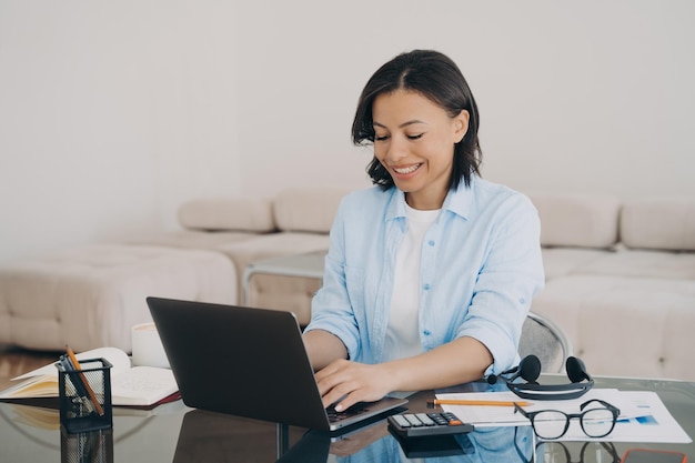 Happy woman is typing text on computer Lady is chatting having conversation with colleague