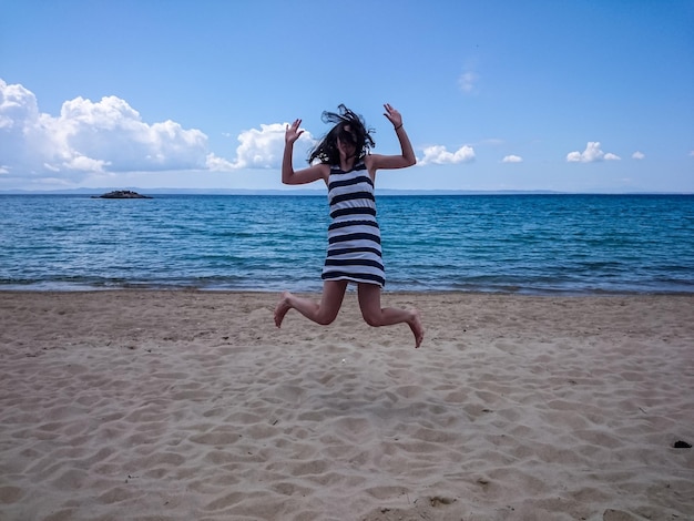 写真 空に向かってビーチでジャンプする幸せな女性