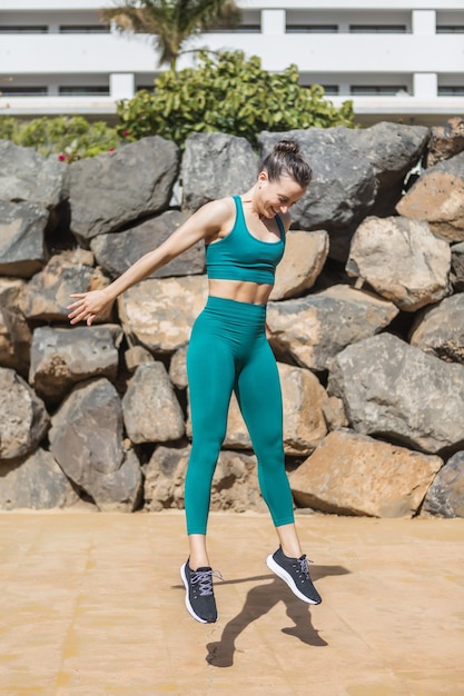 Happy woman jumping near brick wall