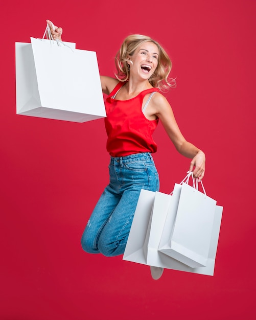 Happy woman jumping with many shopping bags