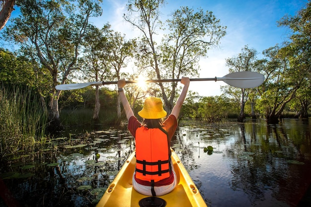 Happy woman kayaking with kayak boat in nuture lake behind sea and beach before sunset time for relax and extreme water sport