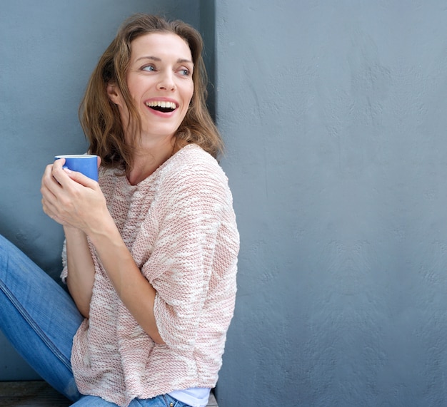 Happy woman laughing with a cup of coffee in hand