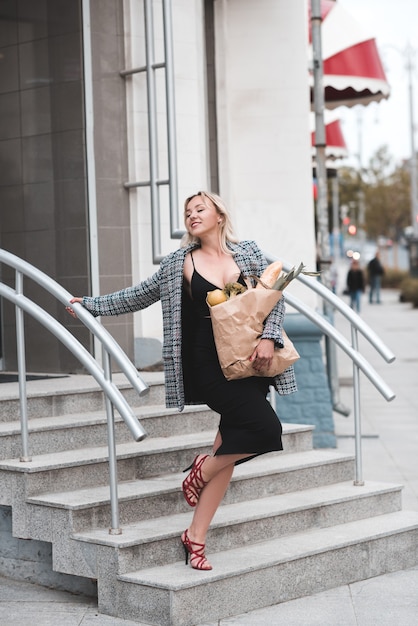 Happy woman leave store with big paper bag full with food outdoors Healthy lifestyle 20s