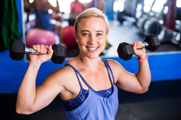  happy woman lifting dumbbell in gym