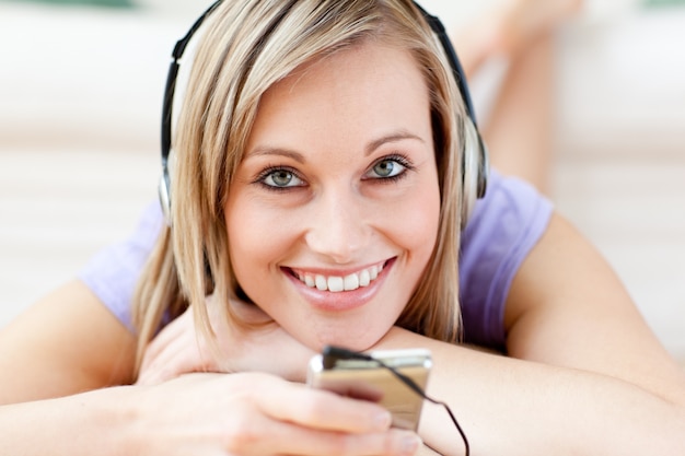 Happy woman listening music lying on the floor 