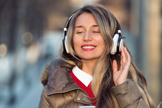 Happy woman listening to music on wireless headphones