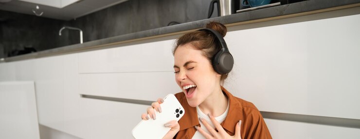Photo 幸せな女性は ⁇ スマートフォンアプリでカラオケを歌って音楽を聴き ⁇ 自宅の床に座っています ⁇ 