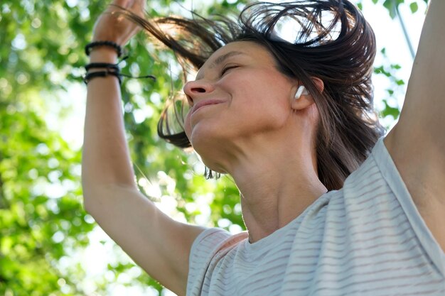 Happy woman listens to music in wireless headphones and dances with her hair flying up