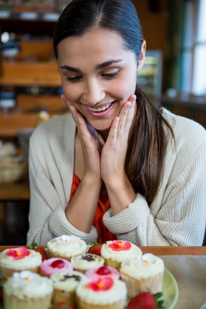 Foto donna felice che esamina un piatto di cupcakes