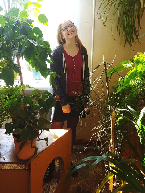 Happy woman looking up while standing by plants at home