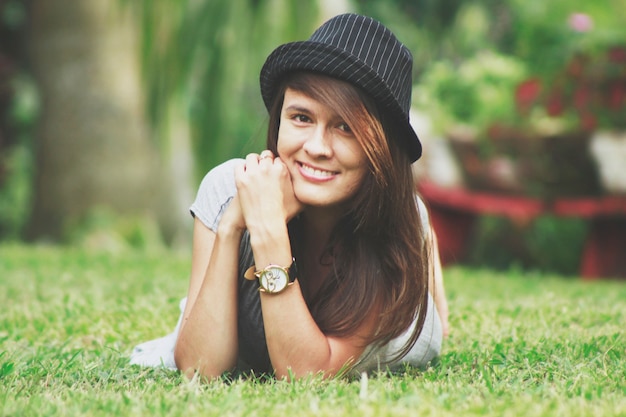 Foto donna felice sdraiata sull'erba con il cappello