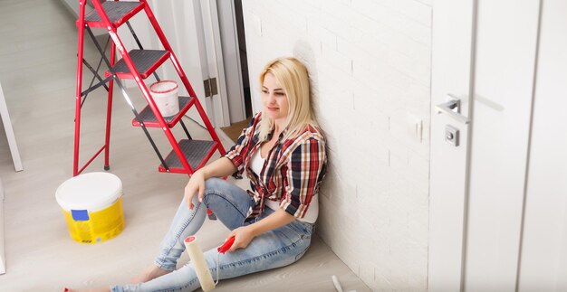 happy woman makes repairs in room at home