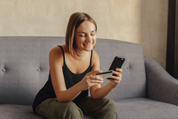 Happy woman making online purchase via smartphone using credit card for payment