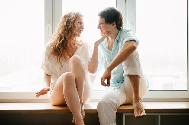 Happy woman and man hugging near window in home on Valentine Day