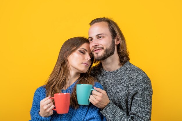幸せな女と男は冬にニットの服を着て、カップ関係からお茶を飲む