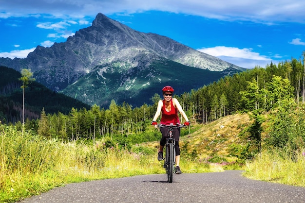 Счастливая женщина на велосипеде MTB на дороге в долине Тича в горах Высоких Татр Словакия