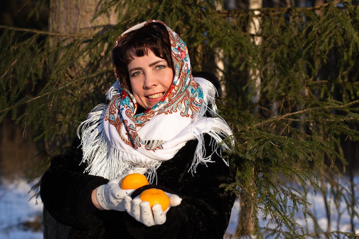 Фотография счастливая женщина на природе зимой с мандаринами