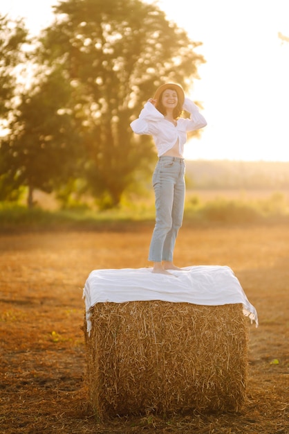 Happy woman near haystack at sunset Fashion concept Nature vacation relax and lifestyle