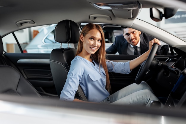 Happy woman new car owner sitting in driver seat and looking around