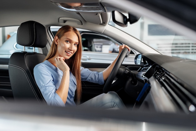 Happy woman new car owner sitting in driver seat