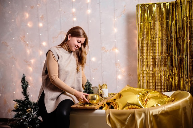 Happy woman in new year's room new year's decoration of the
room in golden color the concept of the holiday and festive design
home decor for the new year