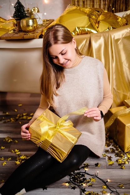 Happy woman in new year\'s room new year\'s decoration of the\
room in golden color the concept of the holiday and festive design\
home decor for the new year